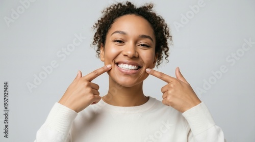 Happy African American woman pointing at her perfect white teeth showing healthy smile and dental hygiene