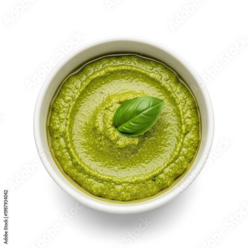 A bowl of vibrant green pesto sauce with a basil leaf garnish