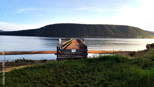 Old wooden pier with caution on russian language - Enter is prohibited. Beautiful river on background