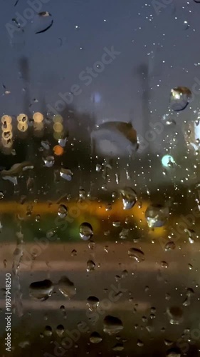 窓ガラスを流れ落ちる雨滴とぼやけた街の明かり