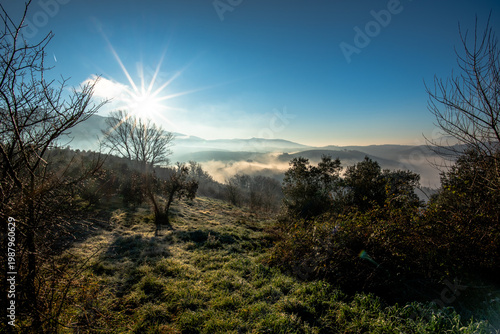 Sunrise over misty hills and frosted field in Italy