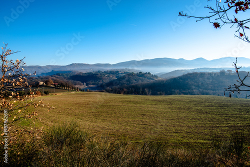 Rolling hills with field and distant village in Italy