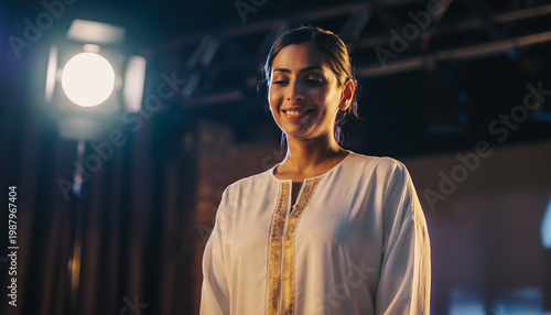 A woman smiling in a professional setting with stage lighting.