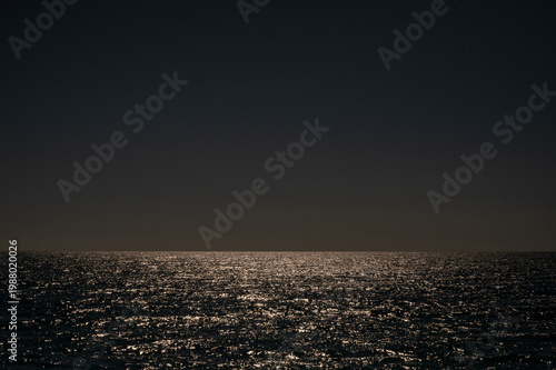 Dark sea horizon at night with moonlight reflection on water