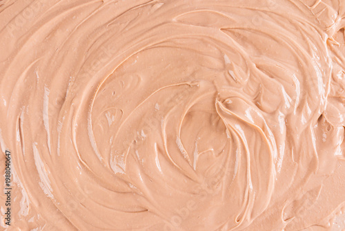 The texture of a delicate buttercream for decorating confectionery. Smooth swirls of cream beige texture. The selective focus