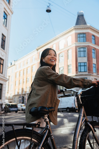 Smiling woman with bicycle in sunny city street