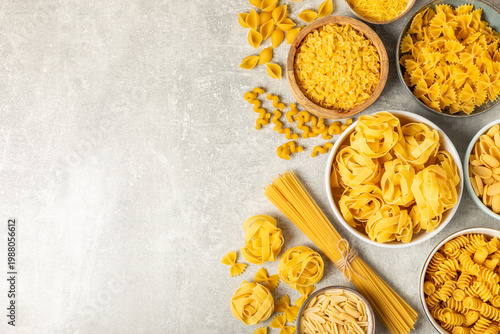 Assorted uncooked pasta in bowls. Variety of Italian dry pasta shapes on textured background, top view. food background. Pasta assortment. raw pasta