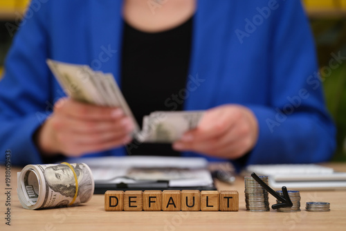 Photos A person in a blue blazer counts cash while sitting at a desk