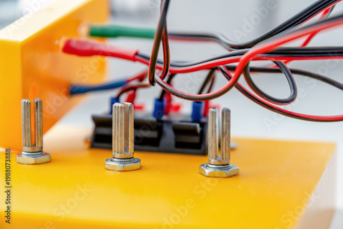 Close-up of electrical wires and terminals on a yellow prototype board. Ideal for STEM education, engineering, and electronics hardware projects