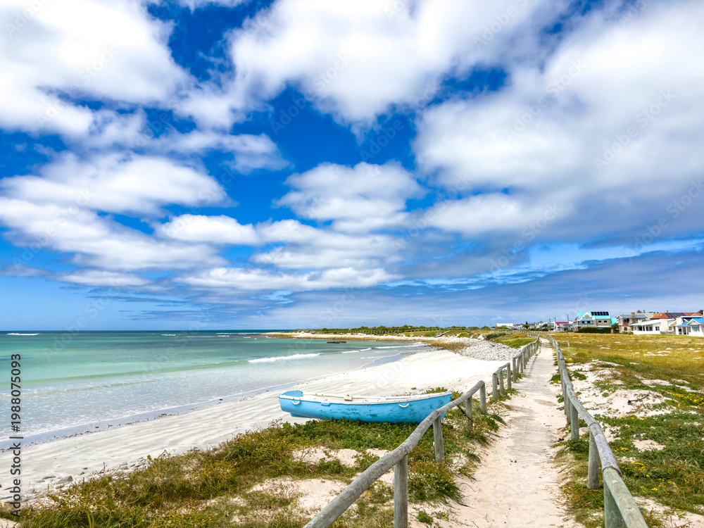 Fototapeta premium Small rowboat dinghy on a beach beneath beautiful blue azure sky