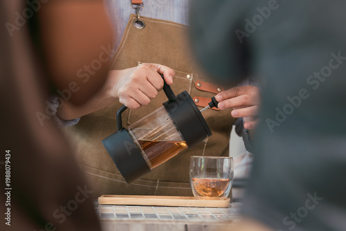 Cuadro en lienzo Over-the-shoulder close-up of a barista pouring handcrafted tea from a modern brewer into a glass