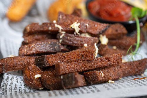 Cuadro en lienzo crispy dark rye garlic croutons sprinkled with grated cheese resting on newspape