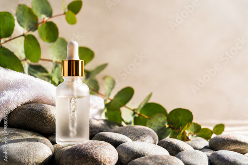 Natural serum bottle with eucalyptus leaves and spa stones for a relaxing skincare ritual
