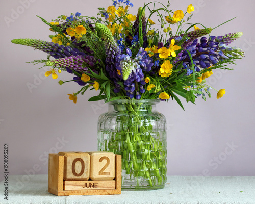 June 2. the date of a festive event, a summer day, or a new beginning. bouquet of lupines and buttercups in a vase.