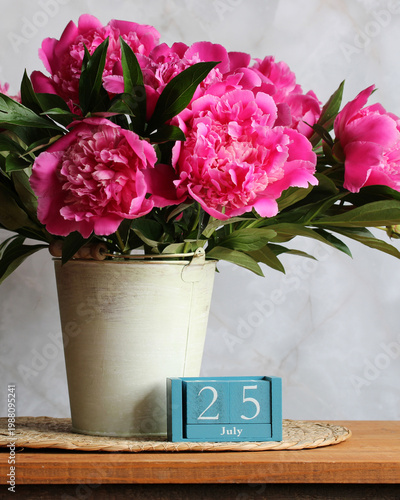 July 25th. the date of the summer day or holiday event. a calendar and a bouquet of garden peonies on a table