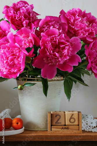 June 26. the date of the summer day or holiday event. a calendar and a bouquet of garden peoniesa table in the cottage.