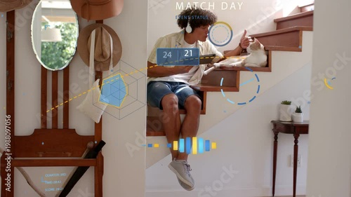 Glancing man wearing headphones checking tablet with MATCH DAY HUD appearing at foyer, stroking cat