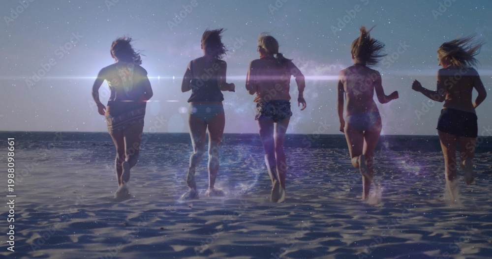 Obraz premium Running five women moving toward ocean at sunset on wet sand, wearing swimsuits and splashing
