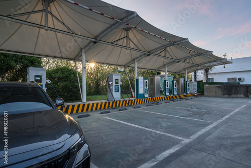 Modern EV Charging Station with Canopy at Dusk, One Car Plugged In