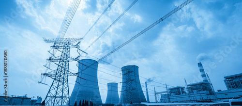 Large Steel Transmission Tower with Multiple Cooling Towers and Power Plant Under Blue Sky