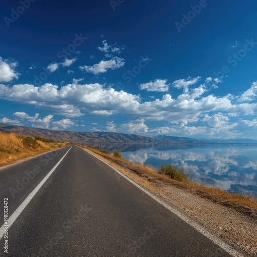 Scenic Road Along Lake Under Bright Blue Sky with White Clouds