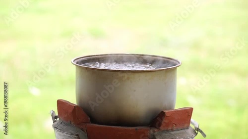 Boiling pot on charcoal stove in countryside, showcasing simple living and mindful energy use.