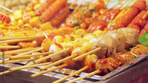 Someone's hands are grilling meatballs on a charcoal grill, creating smoky, juicy, and flavorful bites perfect for a savory meal or outdoor barbecue
