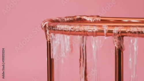 Close-up of metallic structure with translucent material suspended, pink background