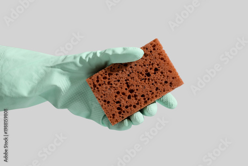 Photography Female hand in rubber glove with brown cleaning sponge on grey background
