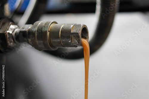 Foto Close up of milky brown contaminated hydraulic oil draining from a metal quick release coupler