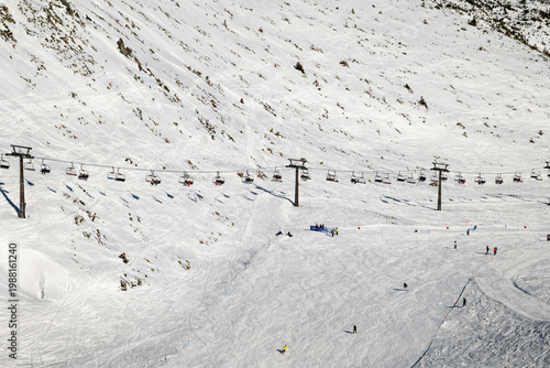 Skiers and snowboarders enjoy snow-covered slopes at a winter resort during daylight hours.Zakopane, Kasprowy Wierch, Tatra mountains, Poland.