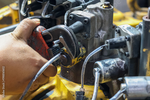 Tableau sur toile Close up of a technician's hand using a heavy duty pipe wrench to install or adjust a solenoid valve on an industrial transmission unit