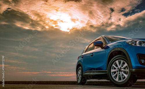Obraz na plátne Blue compact SUV car with sport and modern design parked on concrete road by the sea at sunset in the evening
