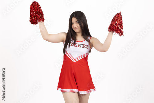 Happy cheerleader jumping with red pompons in the air