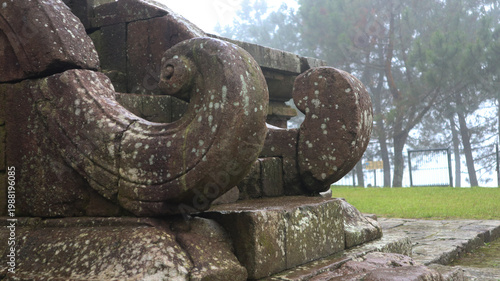 Bild auf Leinwand Weathered ancient stone carving detail at a historical park on a misty morning