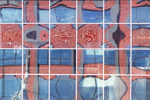 Artistic reflection of a red brick building in glass windows, distorted city pattern, creative architectural abstract background, modern urban design.