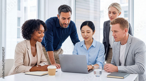 Tableau sur toile Diverse business team collaborating in a modern office, gathered around a laptop, working together on a new project