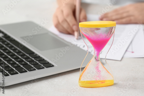 Hourglass with laptop near ...