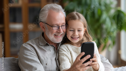Happy grandfather and granddaughter smiling while taking a selfie together at home. Family bonding, love and intergenerational relationships concept.
