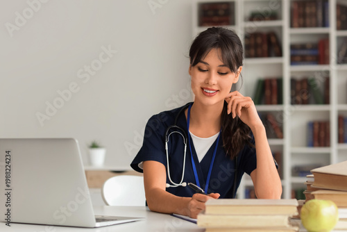 Female medical intern studying at table in library