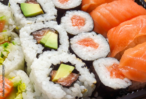 Closeup of a Sushi set. Salmon Sushi Rolls Box, Nori Maki, Nigiri Sushi Roll and uramaki rolls on wooden Background 
