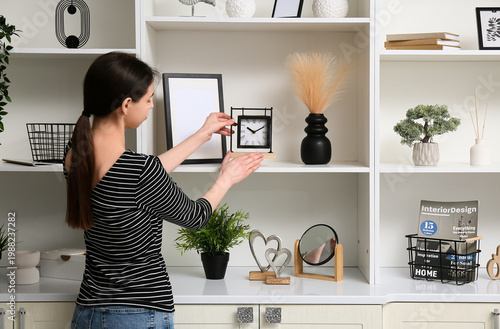 Young woman putting clock o...