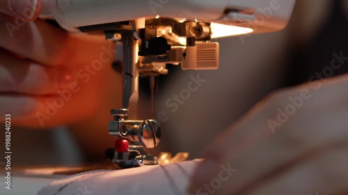 Hands feed blue fabric into a sewing machine, creating neat, even stitches. The close-up showcases the artistry and steady rhythm of the process, emphasizing precision and care.