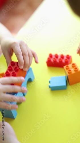 Close-up footage captures two kids' hands building with a construction set. They carefully place each piece, showcasing teamwork, problem-solving, and the excitement of creating something new.