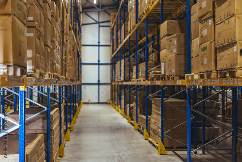Obraz na płótnie Large Industrial Warehouse Aisle With Stacked Boxes on Metal Shelving for Storag