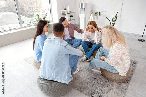 Support group session with stressed woman receiving comfort from therapist an...
