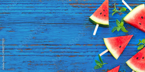 Watermelon Slices on Blue Wooden Plank: Vibrant watermelon slices, speared on sticks, are scattered across a textured blue wooden plank, accented by sprigs of mint.