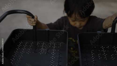 Toddler Playing With Toy Shopping Cart In Restaurant, A video of toddler playing with shopping cart, pushing the mini cart with big smile, for family dining film or childhood documentary.