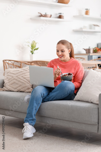 Young woman with laptop eat...