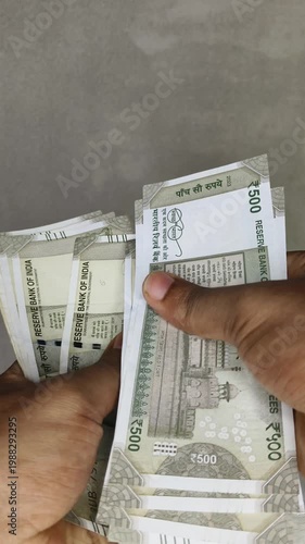 Hand counting bunch of indian currency, money or bank notes bundle of five hundred rupee. Financial, savings, economy, business, salary and investment concept background. Close up vertical top view.